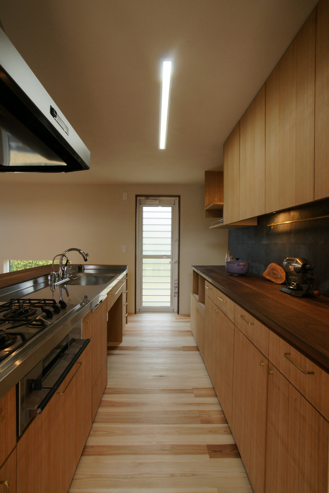 Стильный дизайн: прямая кухня-гостиная в восточном стиле с одинарной мойкой, плоскими фасадами, фасадами цвета дерева среднего тона, светлым паркетным полом, полуостровом, бежевым полом и коричневой столешницей - последний тренд