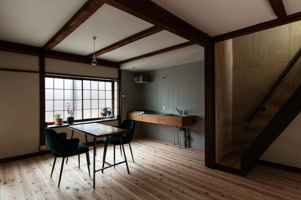 Foto på ett litet funkis grå linjärt kök och matrum, med en integrerad diskho, skåp i mellenmörkt trä, bänkskiva i rostfritt stål, grått stänkskydd, stänkskydd i cementkakel, rostfria vitvaror, ljust trägolv och beiget golv