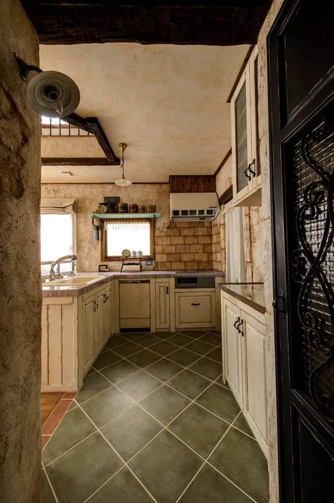 他の地域にあるトラディショナルスタイルのおしゃれなキッチン (ドロップインシンク、レイズドパネル扉のキャビネット、白いキャビネット、黒い床) の写真