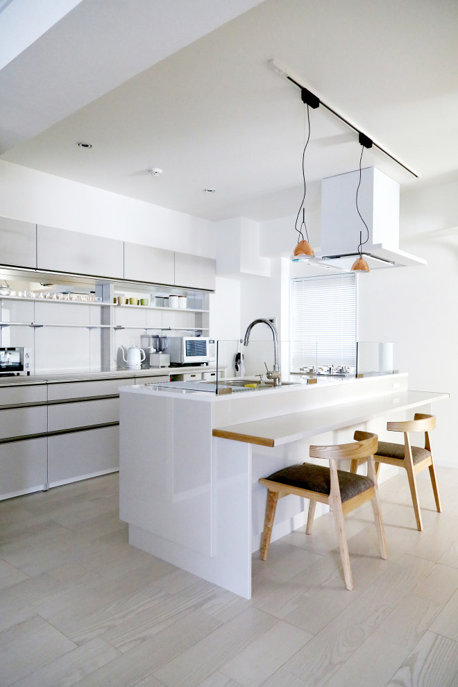 Contemporary kitchen in Tokyo with flat-panel cabinets, grey cabinets, grey splashback, light hardwood flooring, an island, beige floors and grey worktops.