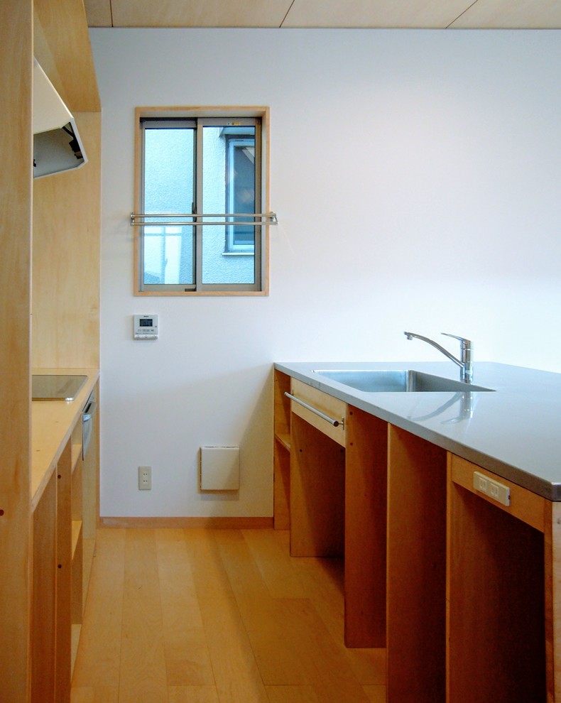 Foto di una piccola cucina scandinava con lavello integrato, ante in legno scuro, top in acciaio inossidabile, paraspruzzi bianco, elettrodomestici in acciaio inossidabile, pavimento in compensato, pavimento beige e top grigio