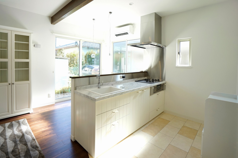 Idéer för att renovera ett mellanstort minimalistiskt linjärt kök med öppen planlösning, med en enkel diskho, vita skåp, bänkskiva i rostfritt stål, vitt stänkskydd, svarta vitvaror, klinkergolv i terrakotta, en köksö, vitt golv och luckor med profilerade fronter