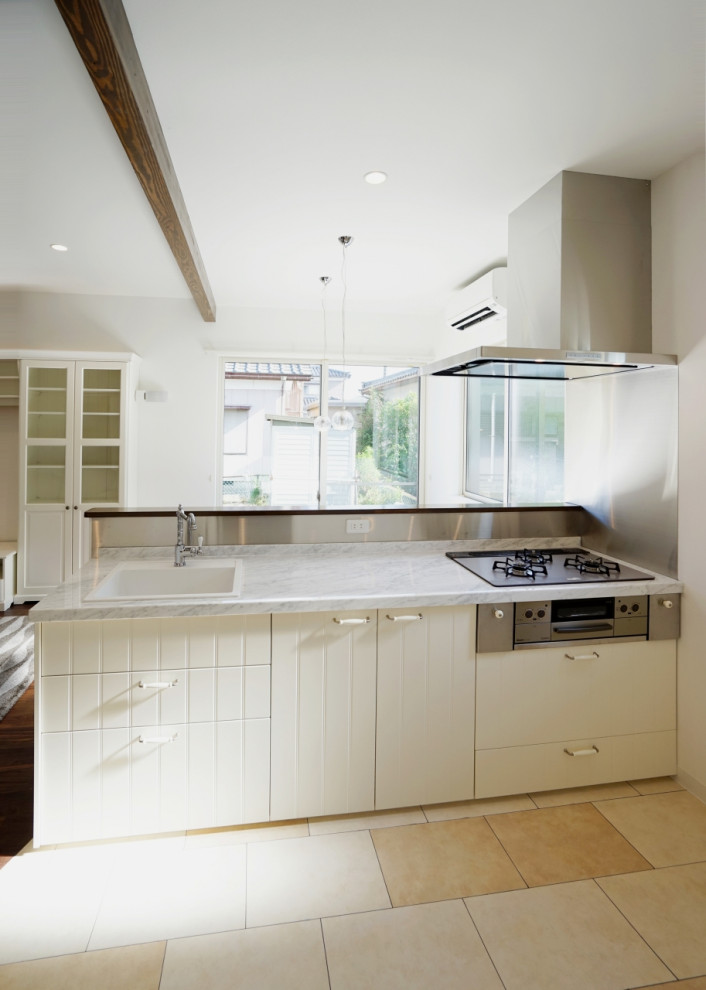 Foto på ett mellanstort skandinaviskt linjärt kök med öppen planlösning, med en enkel diskho, vita skåp, bänkskiva i rostfritt stål, vitt stänkskydd, svarta vitvaror, klinkergolv i terrakotta, en köksö, vitt golv och luckor med profilerade fronter