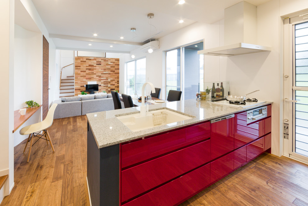 Ispirazione per una cucina design con paraspruzzi rosso, pavimento in legno massello medio e pavimento marrone