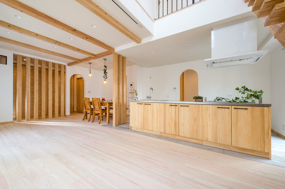 他の地域にある北欧スタイルのおしゃれなキッチン (フラットパネル扉のキャビネット、中間色木目調キャビネット、ステンレスカウンター、淡色無垢フローリング、ベージュの床) の写真