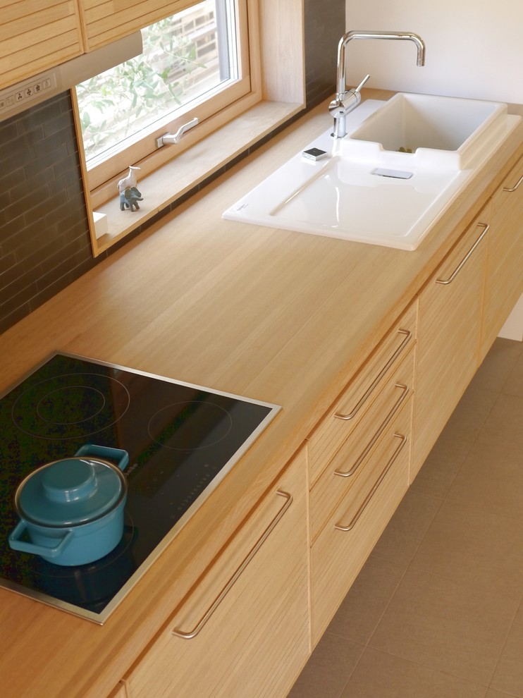 Diseño de cocina lineal nórdica con fregadero encastrado, armarios con paneles lisos, puertas de armario de madera clara, encimera de madera y salpicadero marrón
