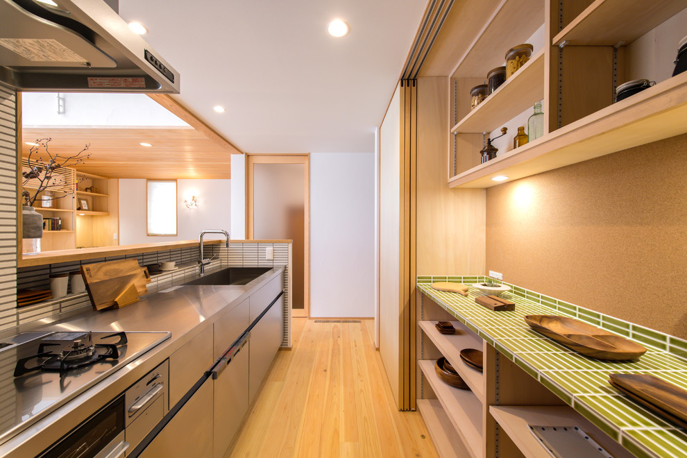 横浜にあるアジアンスタイルのおしゃれなキッチン (シングルシンク、オープンシェルフ、淡色木目調キャビネット、ステンレスカウンター、白いキッチンパネル、セラミックタイルのキッチンパネル、淡色無垢フローリング、茶色い床) の写真