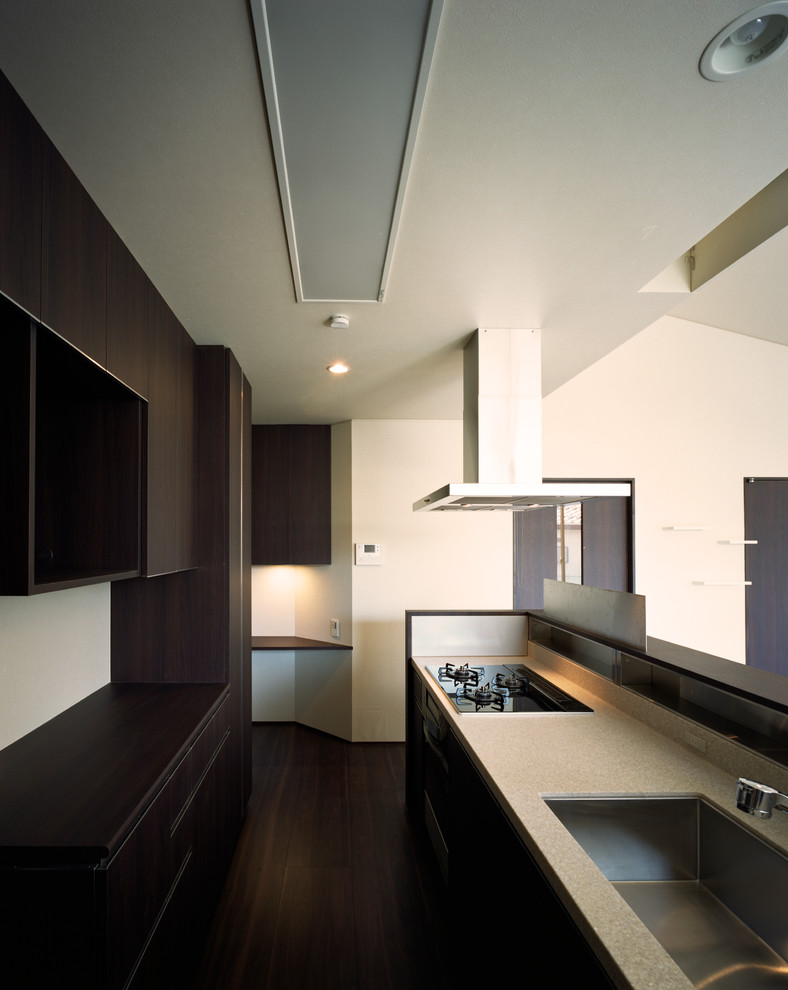 Inspiration för mellanstora moderna linjära vitt kök med öppen planlösning, med en undermonterad diskho, luckor med profilerade fronter, svarta skåp, bänkskiva i koppar, stänkskydd med metallisk yta, glaspanel som stänkskydd, integrerade vitvaror, mörkt trägolv, en köksö och svart golv
