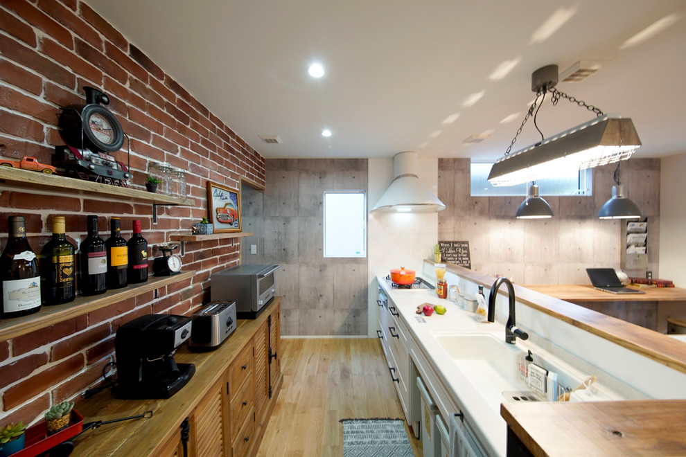 Foto di una cucina ad ambiente unico minimalista con lavello integrato, ante con riquadro incassato, ante bianche, pavimento in legno massello medio, penisola, pavimento marrone e top marrone