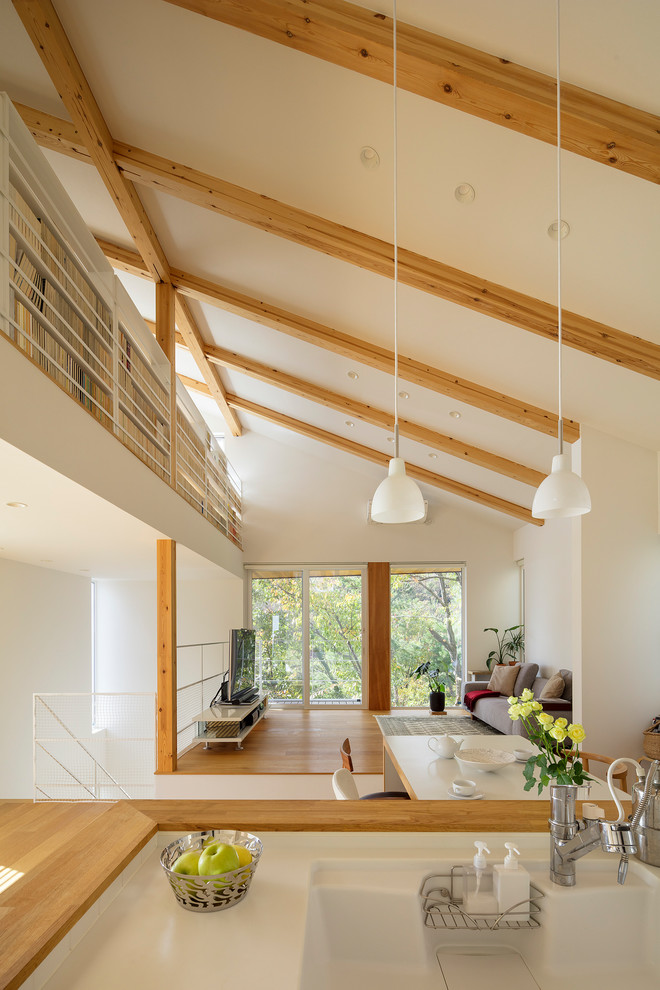 Einzeilige Moderne Wohnküche mit braunem Holzboden und Kücheninsel in Sonstige