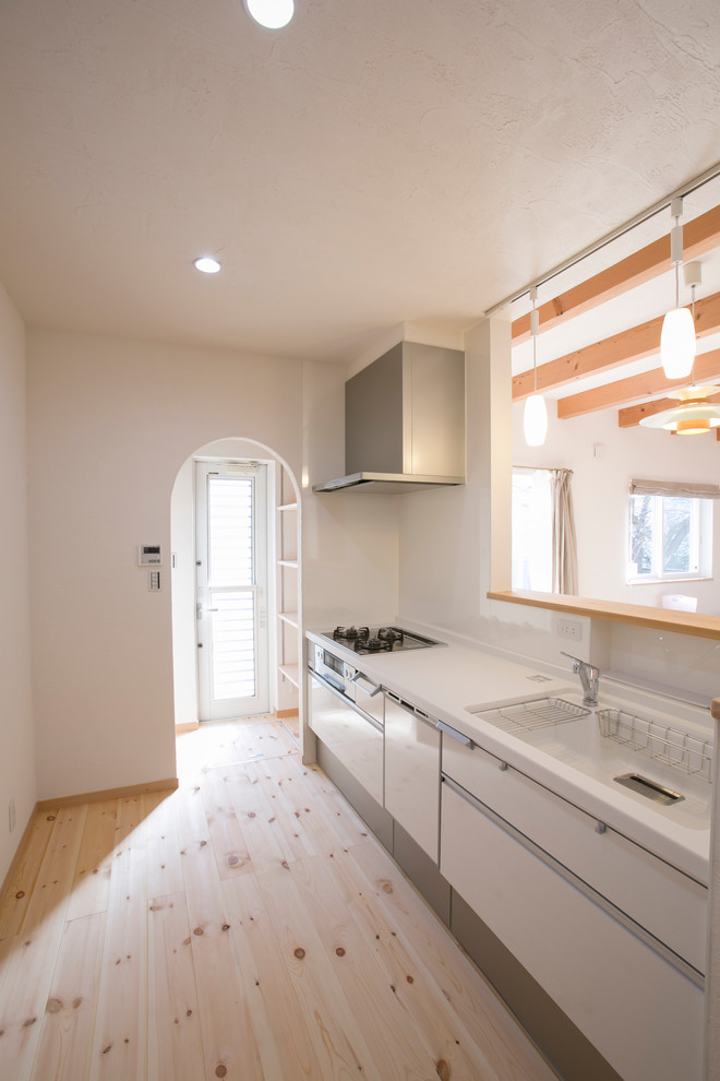 На фото: прямая кухня в стиле модернизм с монолитной мойкой, плоскими фасадами, белыми фасадами, светлым паркетным полом, бежевым полом и бежевой столешницей с