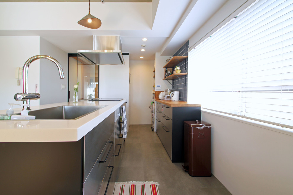 東京23区にあるインダストリアルスタイルのおしゃれなキッチン (ドロップインシンク、フラットパネル扉のキャビネット、グレーのキャビネット、青いキッチンパネル、グレーの床、白いキッチンカウンター) の写真