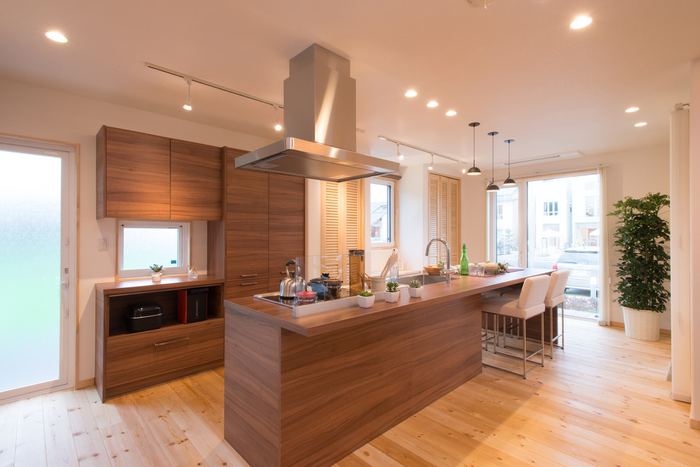 Moderne Küche mit Waschbecken, flächenbündigen Schrankfronten, hellbraunen Holzschränken, Arbeitsplatte aus Holz und hellem Holzboden in Sonstige