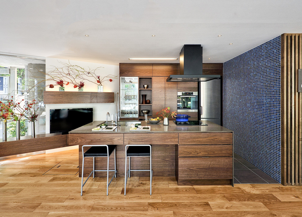 Zweizeilige Moderne Wohnküche mit flächenbündigen Schrankfronten, dunklen Holzschränken, Küchengeräten aus Edelstahl, braunem Holzboden, Kücheninsel und Waschbecken in Tokio