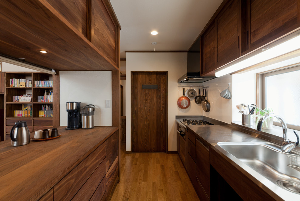 Immagine di una cucina etnica con lavello integrato, ante lisce, ante in legno scuro, pavimento in legno massello medio e pavimento marrone