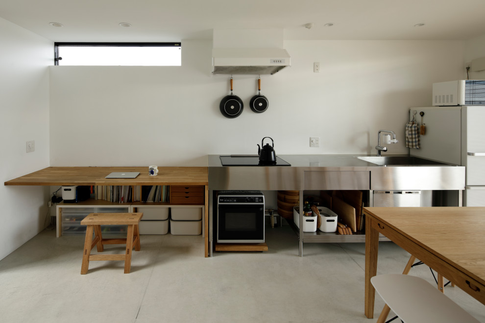Offene, Einzeilige Moderne Küche ohne Insel mit integriertem Waschbecken, Edelstahlfronten, Edelstahl-Arbeitsplatte, Betonboden und grauem Boden in Yokohama