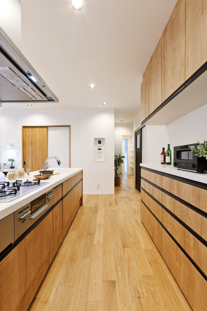 Immagine di una cucina parallela design con ante in legno scuro, pavimento in legno massello medio, pavimento marrone e top bianco