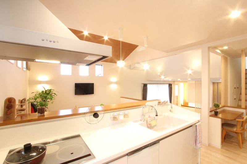 Foto på ett stort funkis vit linjärt kök med öppen planlösning, med släta luckor, vita skåp, bänkskiva i koppar, plywoodgolv, en integrerad diskho, vitt stänkskydd, glaspanel som stänkskydd, vita vitvaror och beiget golv