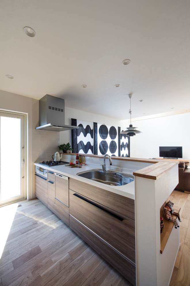 Design ideas for a scandi open plan kitchen in Sapporo with medium wood cabinets, composite countertops, beige splashback, stainless steel appliances, medium hardwood flooring and brown floors.