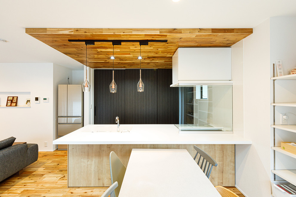 Asiatisk inredning av ett mellanstort vit linjärt vitt kök med öppen planlösning, med en integrerad diskho, släta luckor, skåp i mellenmörkt trä, bänkskiva i koppar, vitt stänkskydd, fönster som stänkskydd, mellanmörkt trägolv, en halv köksö och brunt golv