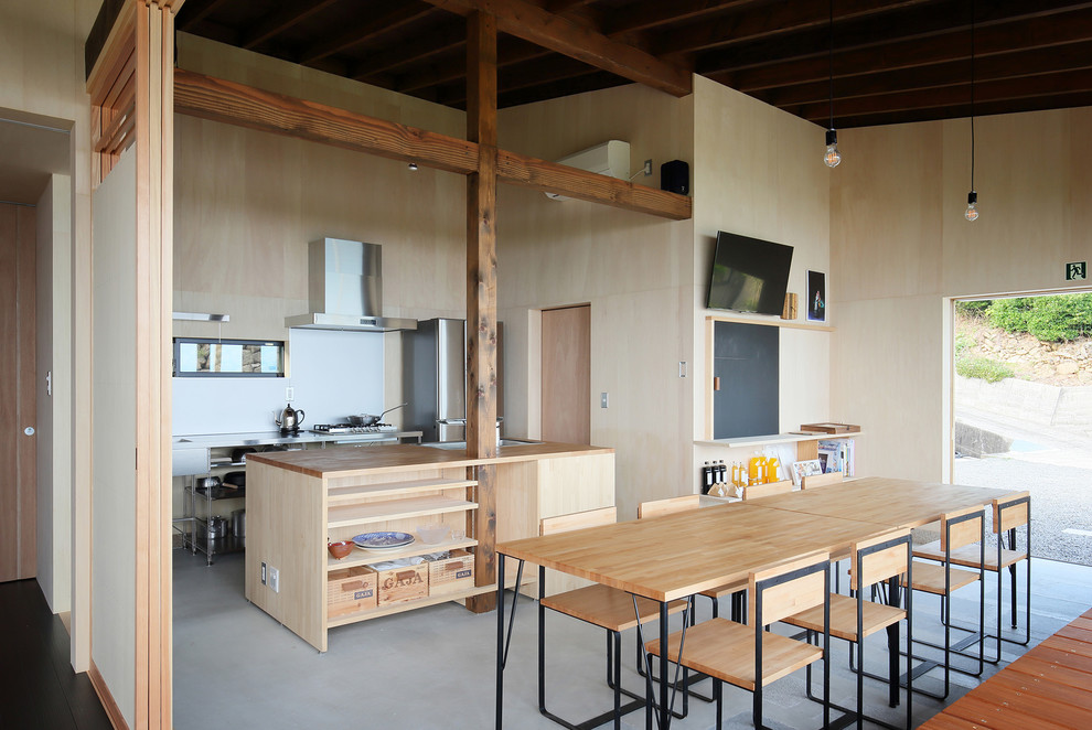 Cette photo montre une cuisine ouverte parallèle asiatique avec un évier 1 bac, un placard sans porte, un plan de travail en bois, îlot et un sol gris.