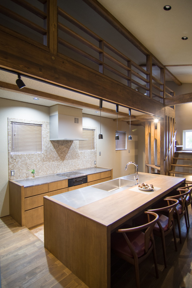 Aménagement d'une cuisine ouverte parallèle contemporaine en bois brun avec un évier intégré, un placard à porte plane, un plan de travail en inox, une crédence beige, îlot et un plan de travail marron.