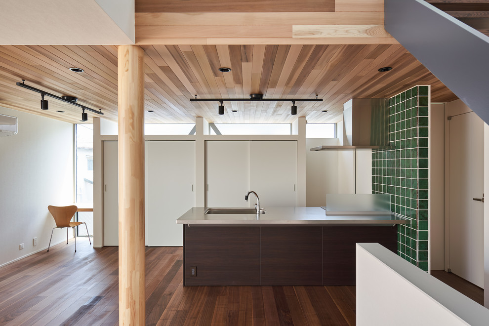 Foto på ett funkis linjärt kök med öppen planlösning, med en enkel diskho, mörkt trägolv, en halv köksö och brunt golv