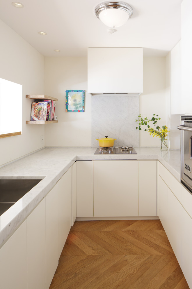Immagine di una cucina ad U chiusa con ante bianche, paraspruzzi grigio, ante lisce e paraspruzzi in lastra di pietra
