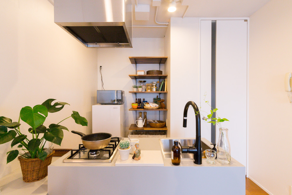 Esempio di una cucina lineare minimalista con lavello a vasca singola, pavimento in legno massello medio, penisola e pavimento marrone