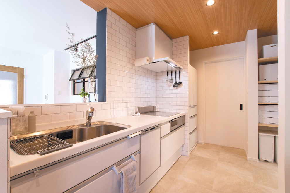 Modern inredning av ett litet vit linjärt vitt kök med öppen planlösning, med släta luckor, skåp i ljust trä, bänkskiva i koppar, vitt stänkskydd, stänkskydd i tunnelbanekakel, vita vitvaror, en halv köksö, beiget golv och en enkel diskho