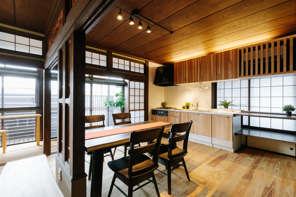 Exempel på ett litet asiatiskt vit linjärt vitt kök och matrum, med en undermonterad diskho, skåp i mellenmörkt trä, bänkskiva i koppar, vitt stänkskydd, stänkskydd i trä, svarta vitvaror, mellanmörkt trägolv, en köksö och beiget golv