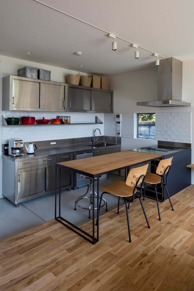 Foto på ett mellanstort funkis grå linjärt kök med öppen planlösning, med skåp i rostfritt stål, bänkskiva i rostfritt stål, vitt stänkskydd, stänkskydd i keramik, färgglada vitvaror och en köksö
