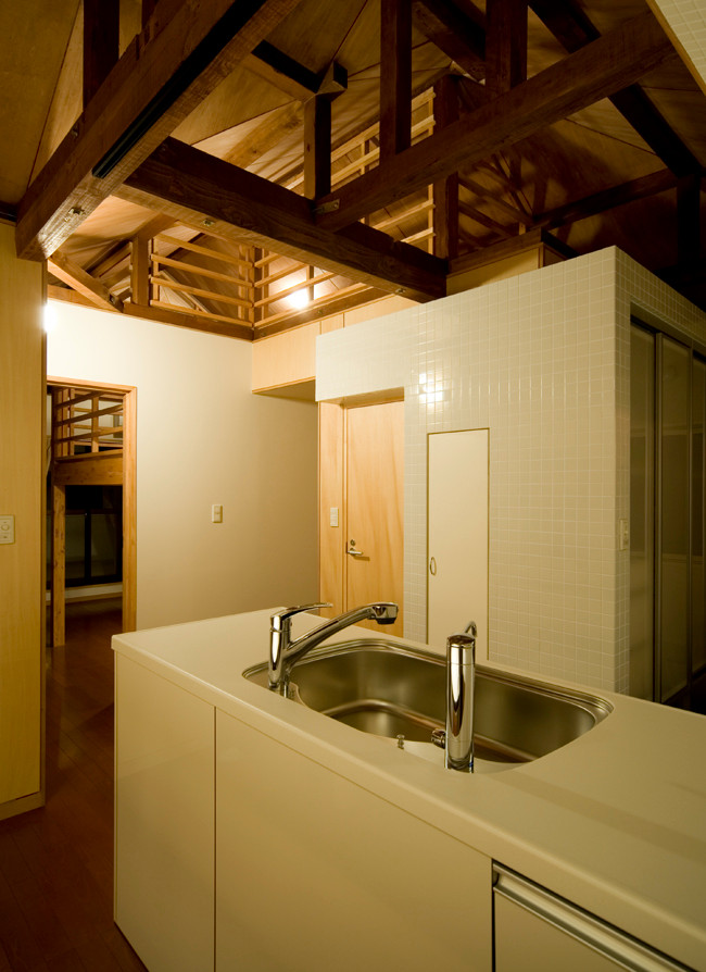 Foto på ett litet funkis vit kök, med en nedsänkt diskho, luckor med glaspanel, vita skåp, bänkskiva i koppar, vitt stänkskydd, stänkskydd i keramik, rostfria vitvaror, plywoodgolv och brunt golv