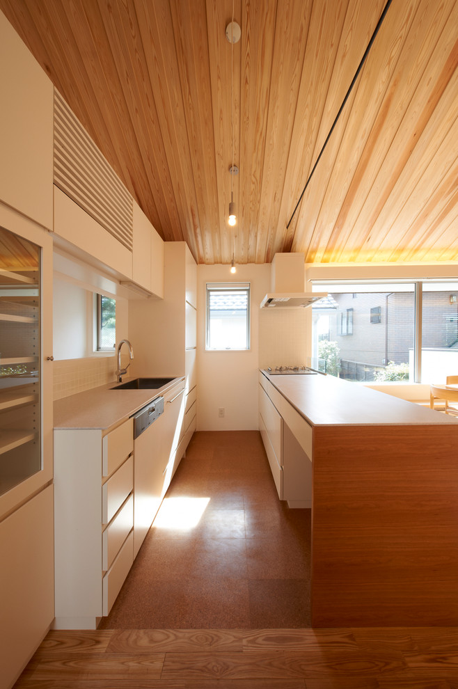 Zweizeilige Asiatische Küche mit Waschbecken, flächenbündigen Schrankfronten, weißen Schränken, Küchenrückwand in Weiß, braunem Holzboden, Kücheninsel und braunem Boden in Tokio