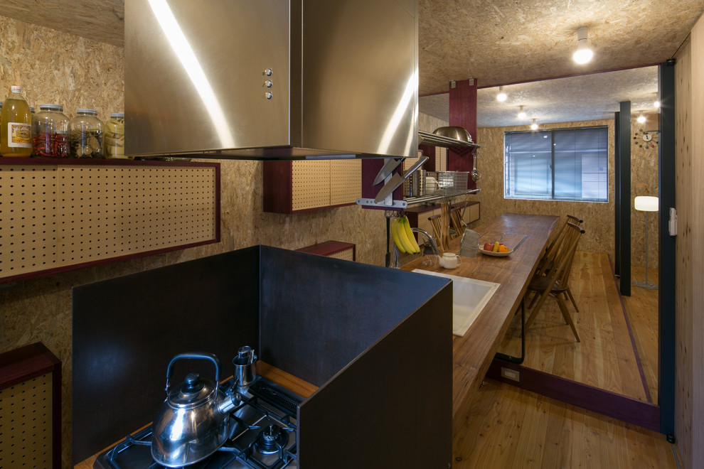 Exemple d'une cuisine linéaire industrielle avec un évier posé, un plan de travail en bois, une crédence marron, un électroménager en acier inoxydable, un sol en bois brun et îlot.
