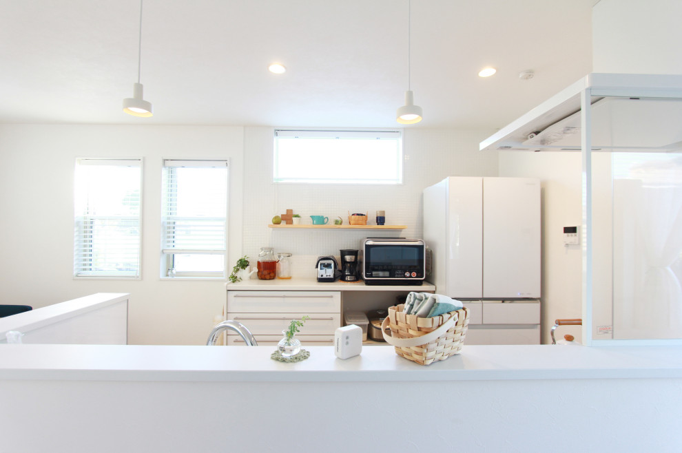 Photo of a medium sized scandinavian single-wall open plan kitchen in Tokyo Suburbs with an integrated sink, flat-panel cabinets, white cabinets, composite countertops, white splashback, ceramic splashback, white appliances, medium hardwood flooring, a breakfast bar, brown floors and white worktops.