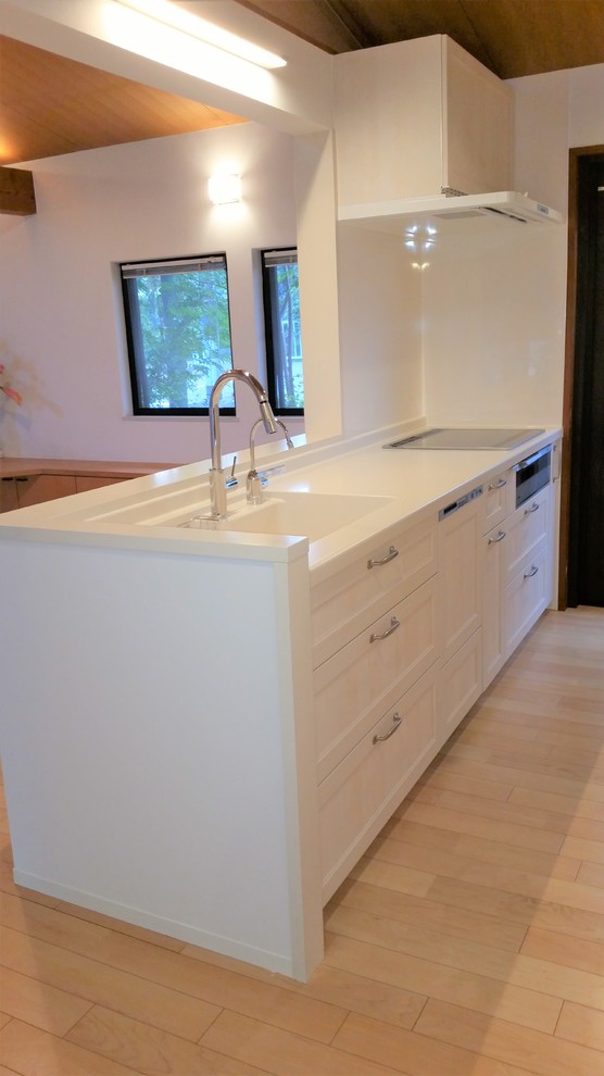 Foto di una cucina shabby-chic style di medie dimensioni con lavello integrato, ante bianche, top in superficie solida, paraspruzzi bianco, elettrodomestici in acciaio inossidabile e pavimento in compensato