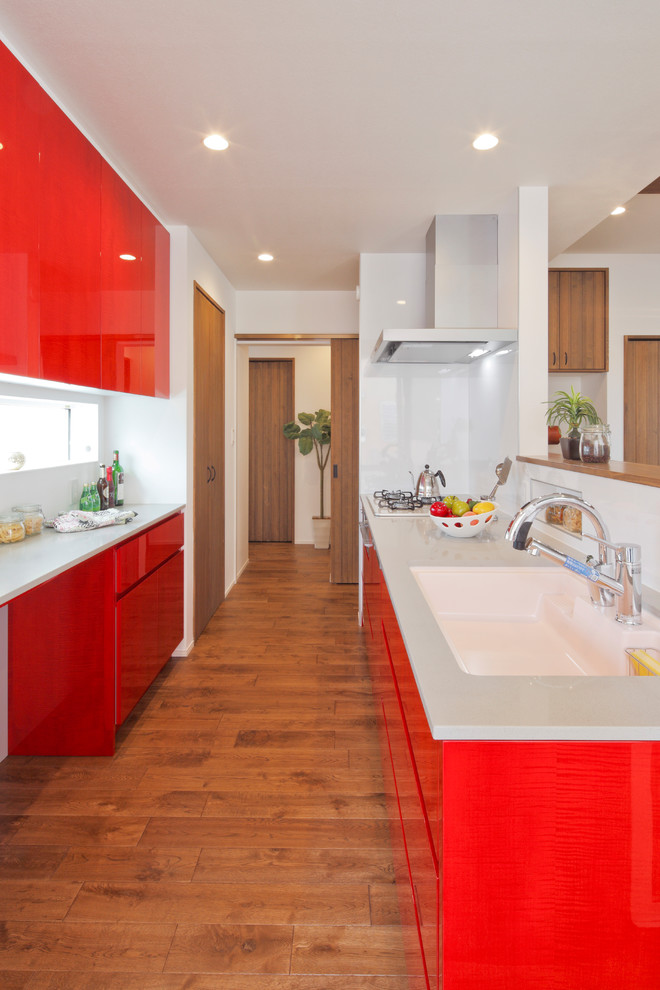 Идея дизайна: параллельная кухня-гостиная в современном стиле с красными фасадами, паркетным полом среднего тона и коричневым полом
