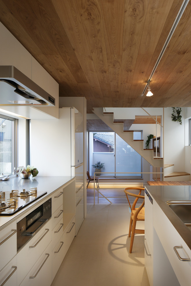 Skandinavisk inredning av ett kök, med släta luckor, vita skåp, bänkskiva i rostfritt stål och en köksö