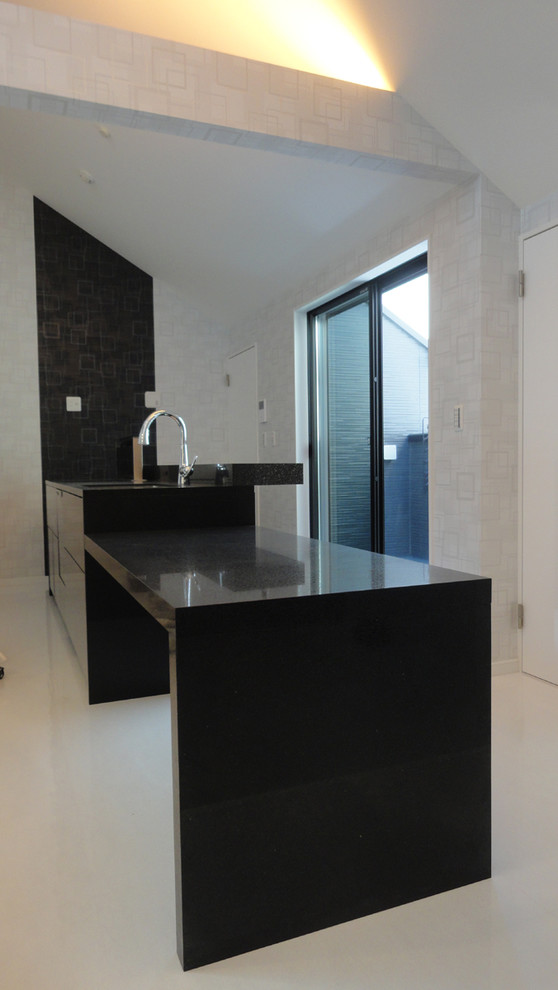 Foto di un cucina con isola centrale design con lavello sottopiano, ante lisce, top in quarzo composito e top nero