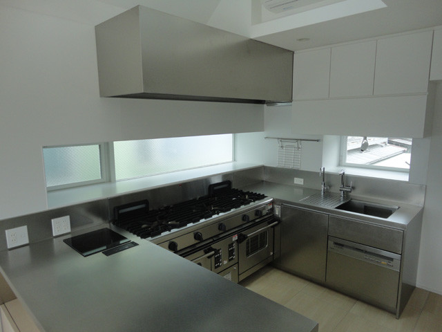 This is an example of an urban u-shaped kitchen in Other with an integrated sink, flat-panel cabinets, grey cabinets, stainless steel worktops, metallic splashback and grey worktops.