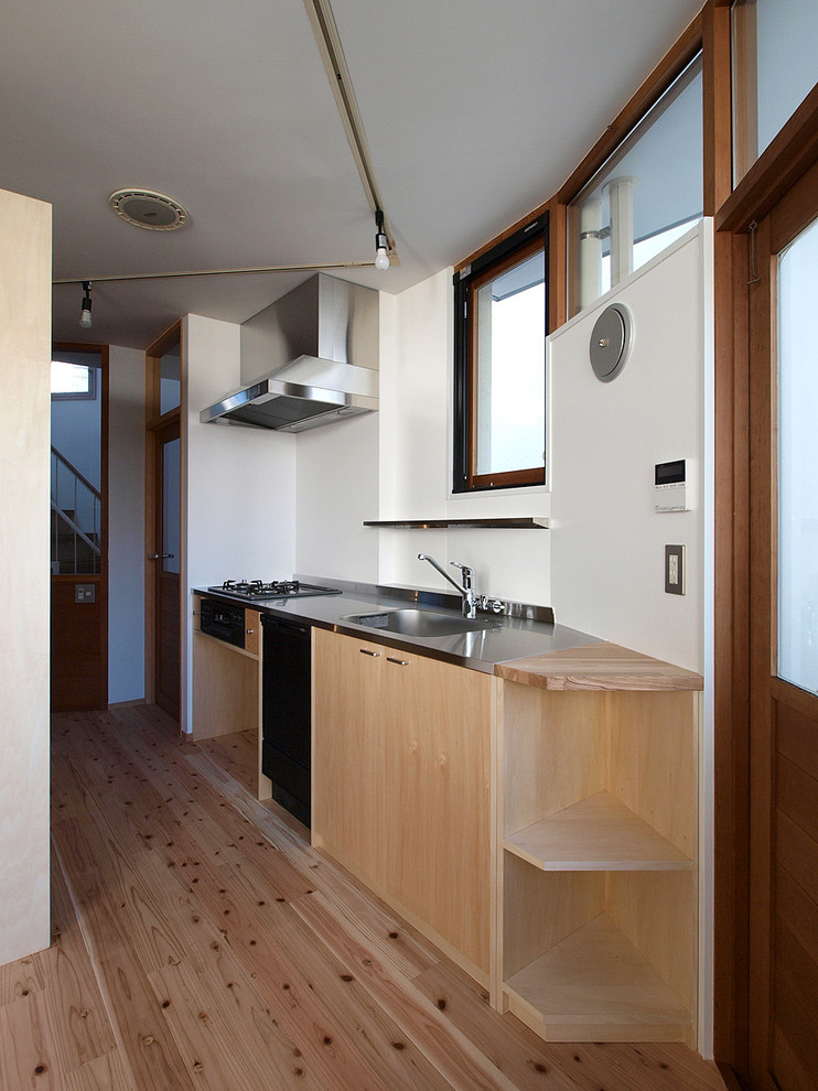 Aménagement d'une cuisine ouverte linéaire scandinave en bois clair avec un placard à porte plane, un plan de travail en inox, une crédence blanche, parquet clair, aucun îlot et un sol beige.