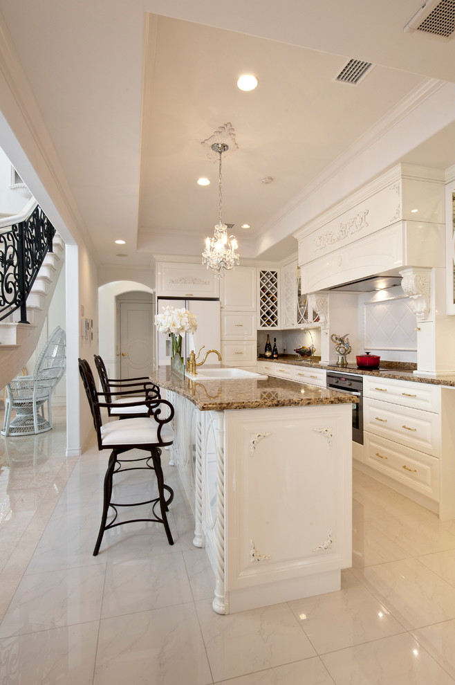 Foto di una cucina vittoriana con lavello da incasso, ante con bugna sagomata, ante bianche, top in granito, pavimento in marmo e pavimento beige
