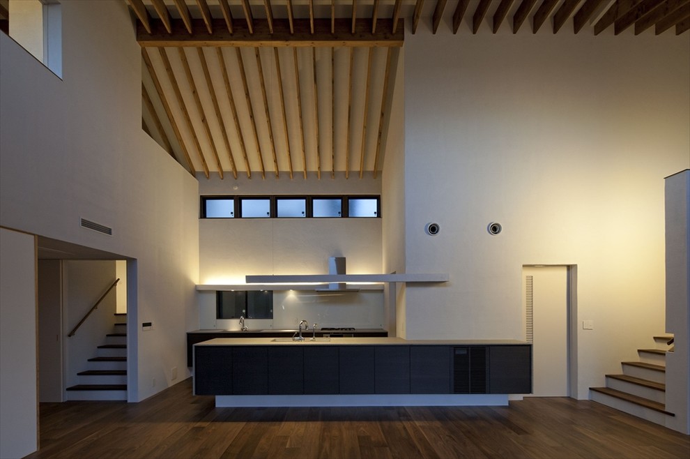 Cette photo montre une cuisine ouverte parallèle moderne de taille moyenne avec des portes de placard noires, un électroménager en acier inoxydable, parquet foncé et une péninsule.