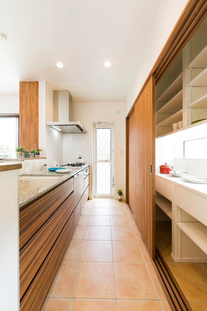 Modelo de cocina campestre abierta con puertas de armario de madera oscura, encimera de granito, electrodomésticos de acero inoxidable, suelo de baldosas de porcelana, suelo beige y encimeras blancas