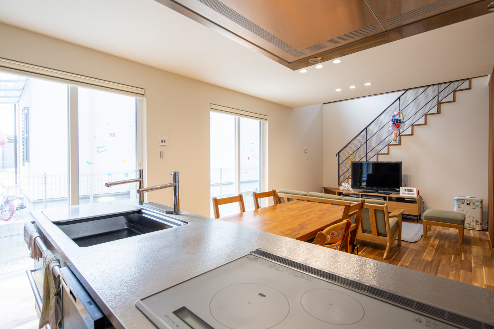 Aménagement d'une cuisine ouverte linéaire moderne avec un plan de travail en inox, un sol en bois brun, une péninsule et un plafond en papier peint.