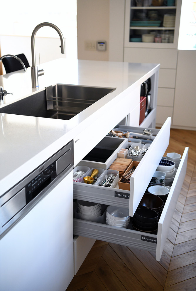 北欧スタイルのおしゃれなキッチン (アンダーカウンターシンク、インセット扉のキャビネット、白いキャビネット、白いキッチンパネル、白い調理設備、淡色無垢フローリング、茶色い床) の写真