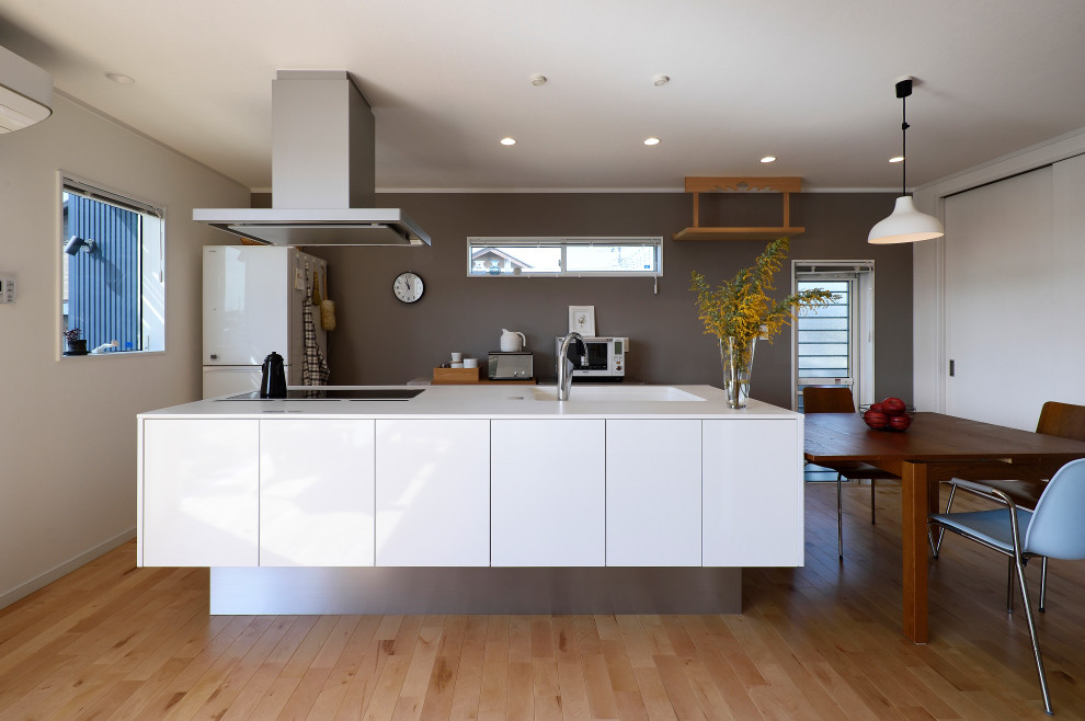Modern inredning av ett vit linjärt vitt kök med öppen planlösning, med bänkskiva i koppar, vitt stänkskydd, mellanmörkt trägolv, en köksö och brunt golv