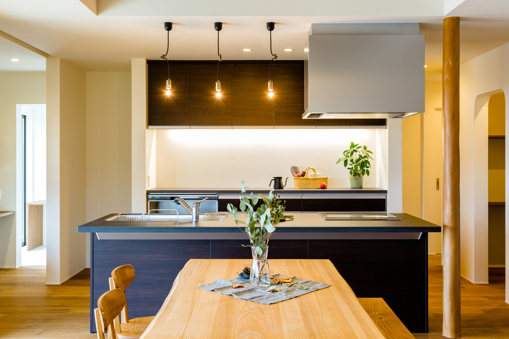 Einzeilige Moderne Küche mit Waschbecken, flächenbündigen Schrankfronten, dunklen Holzschränken, braunem Holzboden, Kücheninsel und braunem Boden in Nagoya