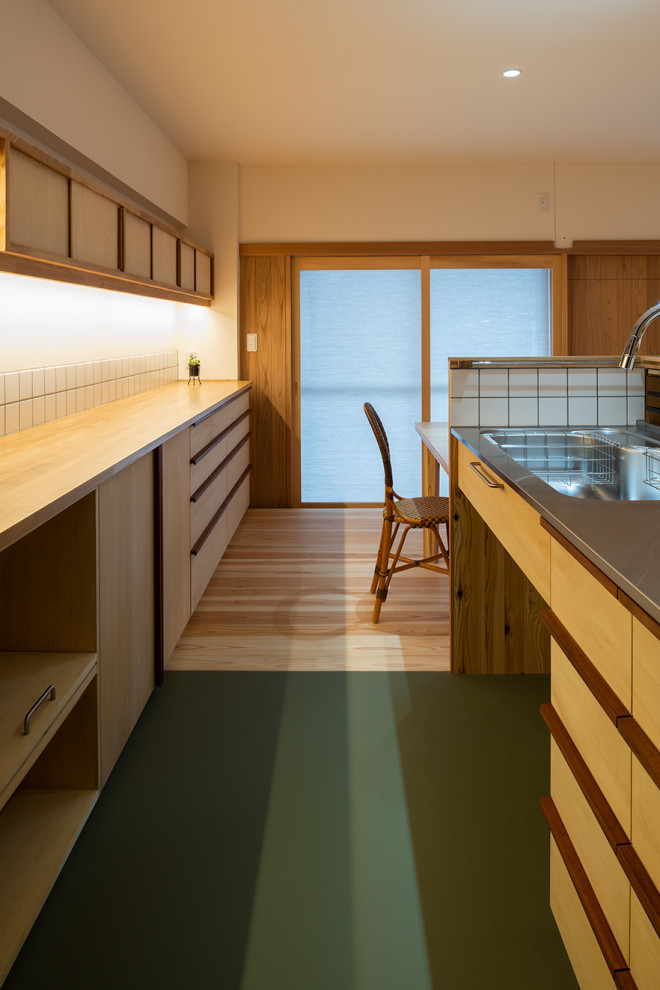 東京都下にあるトラディショナルスタイルのおしゃれなキッチン (シングルシンク、インセット扉のキャビネット、中間色木目調キャビネット、ステンレスカウンター、木材のキッチンパネル、リノリウムの床、緑の床) の写真